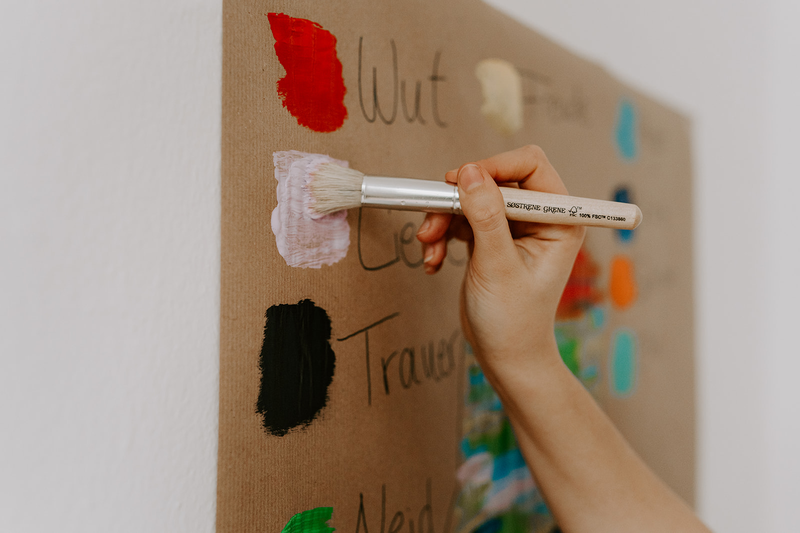 Eine Hand hält einen Pinsel, der mit weißer Farbe an einer Wandtafel malt