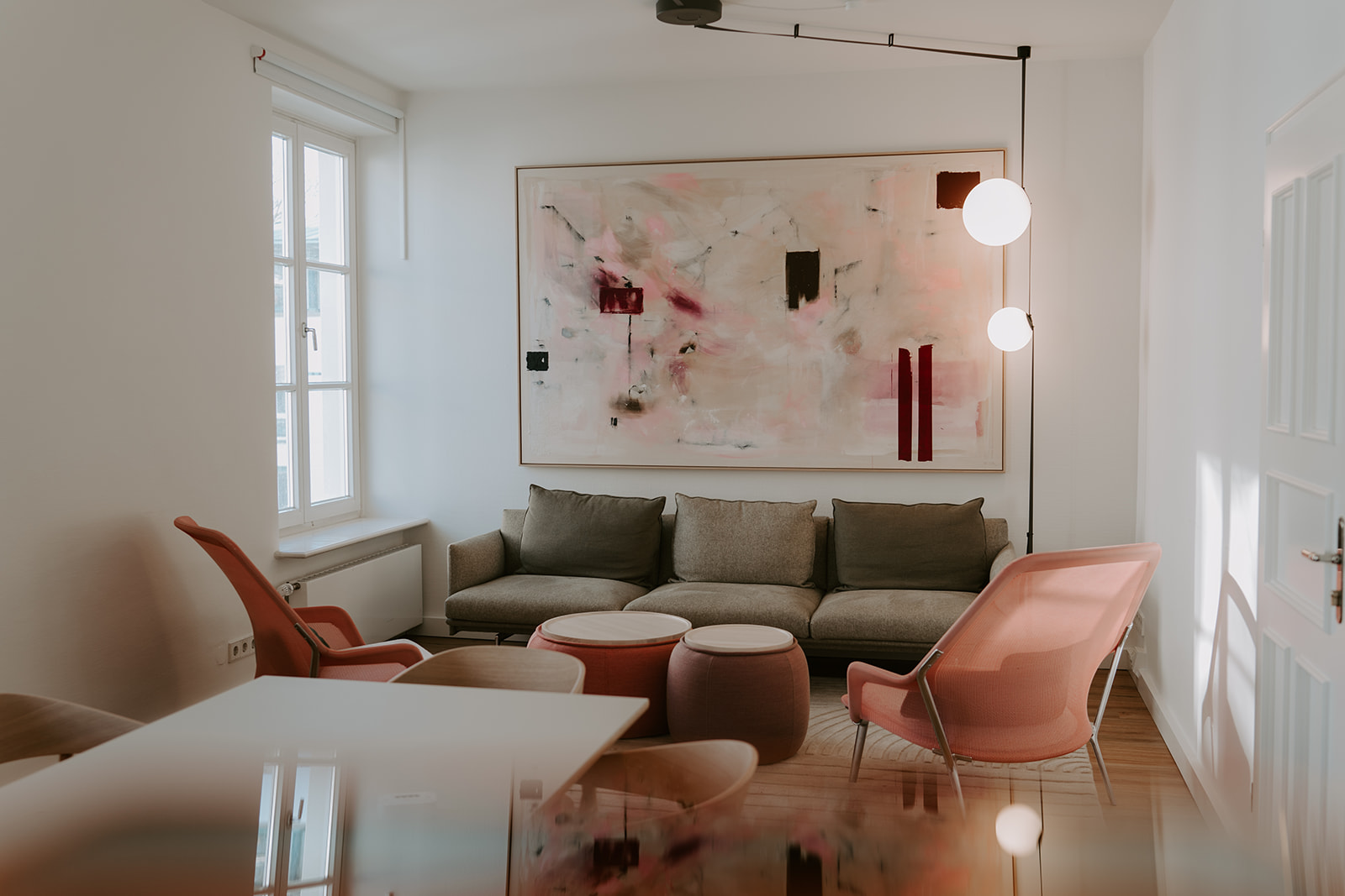 Ein Konferenzraum mit Tisch im Vordergrund und Sitzgruppe im Hintergrund und ein Gemälde an der Wand