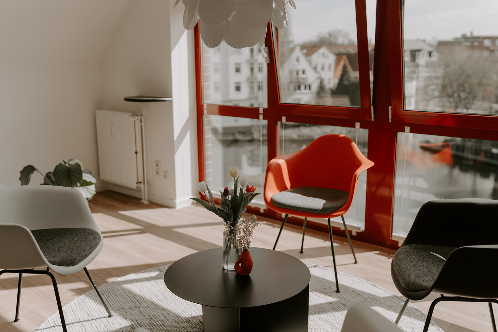Eine Sitzgruppe aus drei Loungechairs im Hintergrund ein Fenster mit Blick auf ein Gewässer
