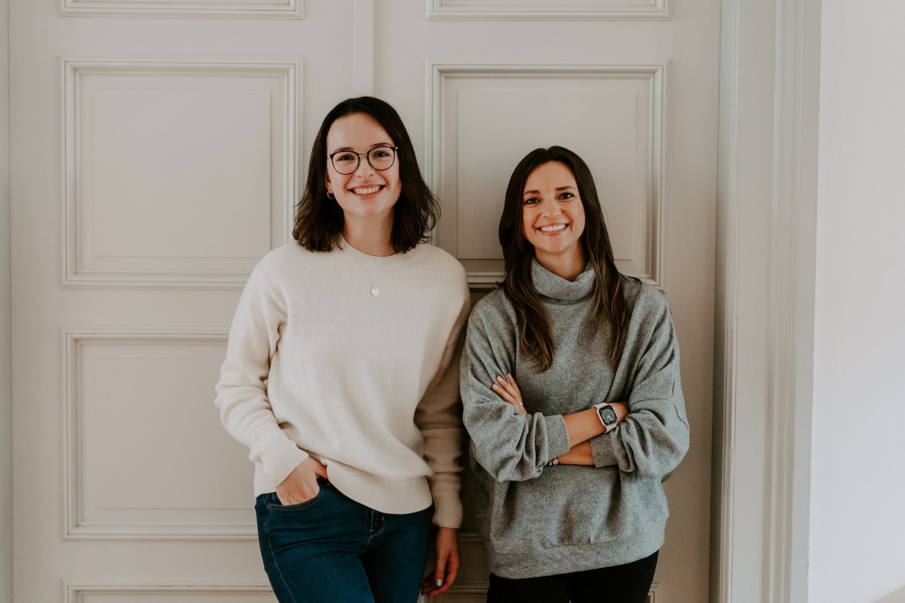 Die Therapeutinnen Lea Sophie Schäfer und Larissa Dietz stehen vor einer Holztür in der Praxis Eimsbüttel