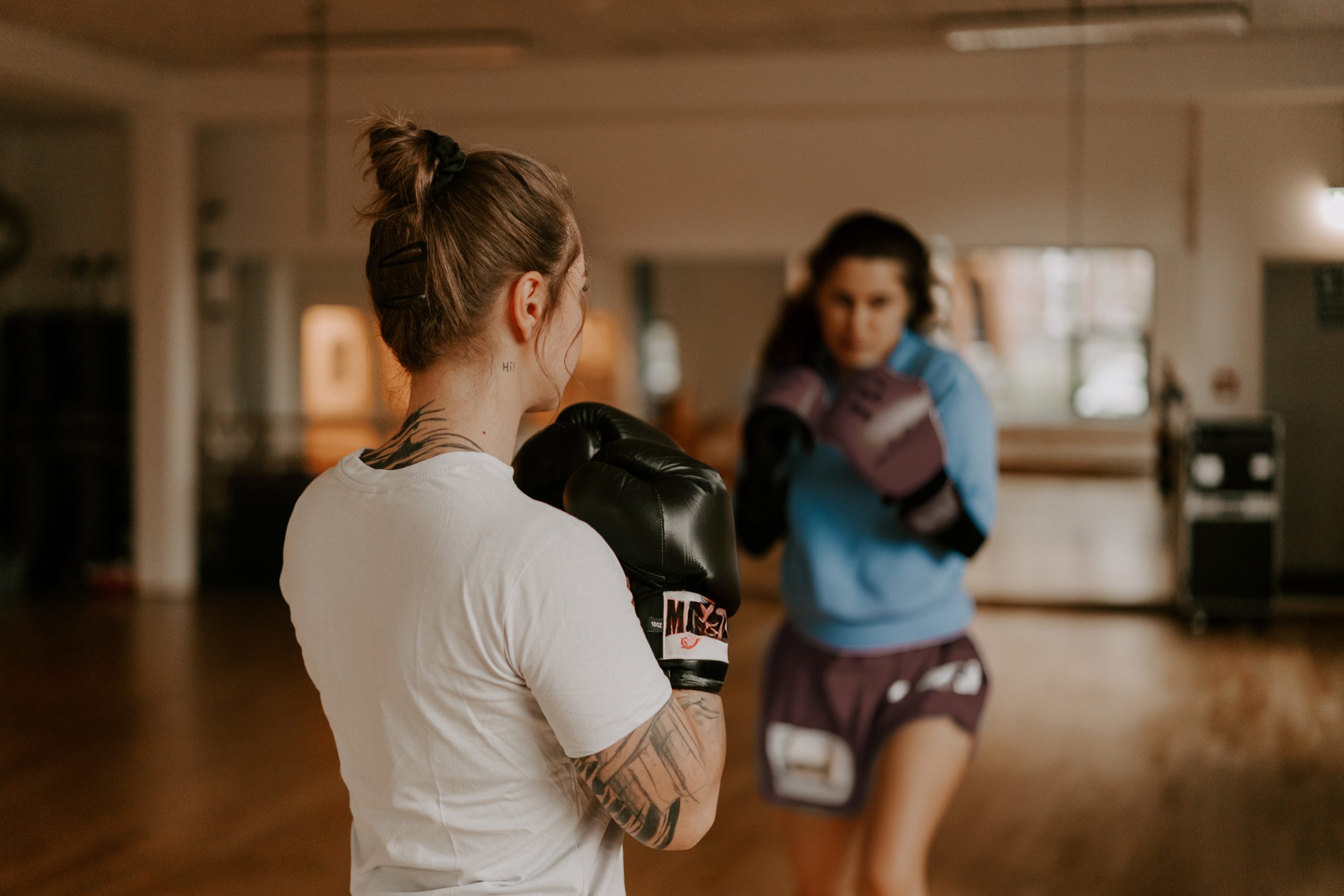 Die Familientherapeutin Mona Friedrichs steht mit dem Rücken zu einer anderen Person beim Thaibox-Training in einem Studio
