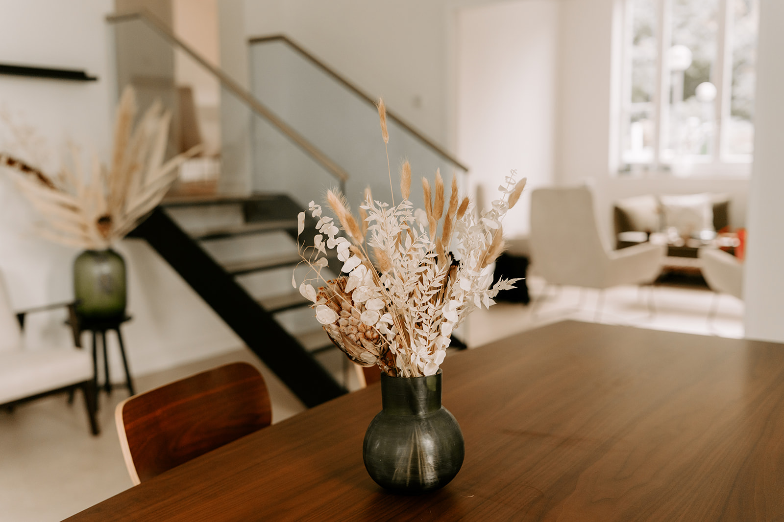 Ein dunkler Holztisch mit einer Blumenvase mit Trockenblumen