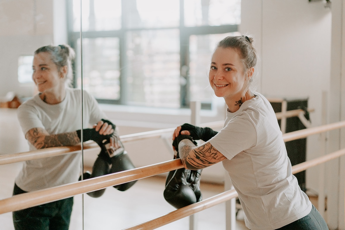 Die Familientherapeutin Mona Friedrichs steht in einem Sportstudio an eine Ballettstange gelehnt vor einem Spiegel